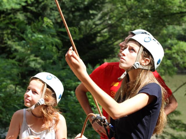 Fillette et adolescente pratiquant l'escalade en colonie de vacances à la montagne