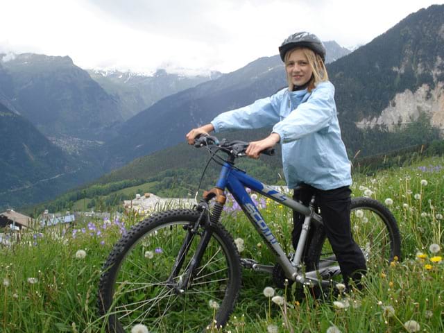 Jeune fille faisant du vélo en colonie de vacances à la montagne 