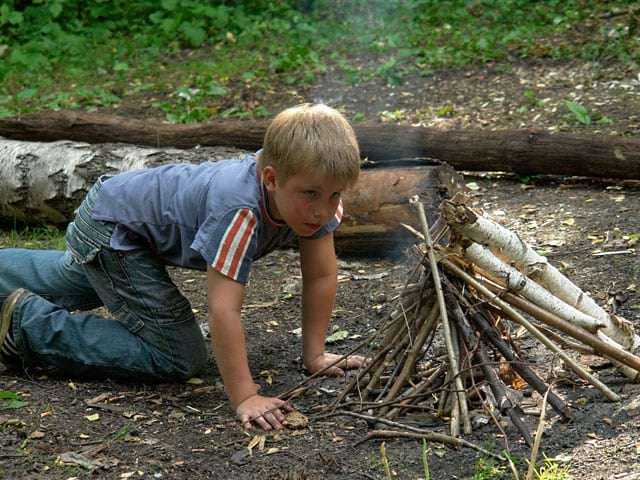 Enfant apprenant à faire du feu en colonie de vacances à la mpntage