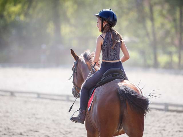 Jeune fille en balade à cheval en colo équitation été