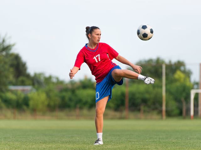 Jeune fille faisant du football en stage sportif cet été