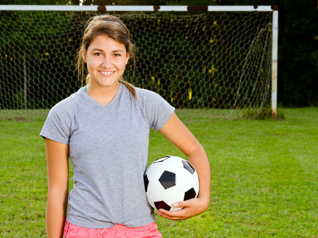 Jeune fille qui joue au football en colonie de vacances