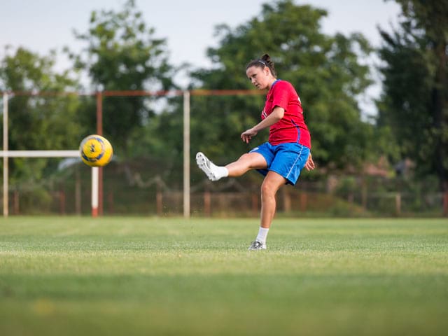 Adolescente faisant du football cet été en stage sportif 