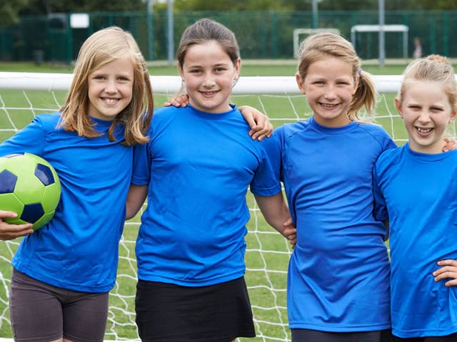 groupe d'enfants souriants en stage sportif de football féminin