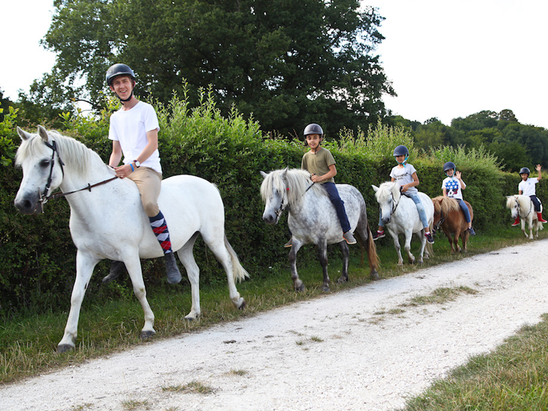Enfants à cheval en colonie de vacances à la ferme cet été