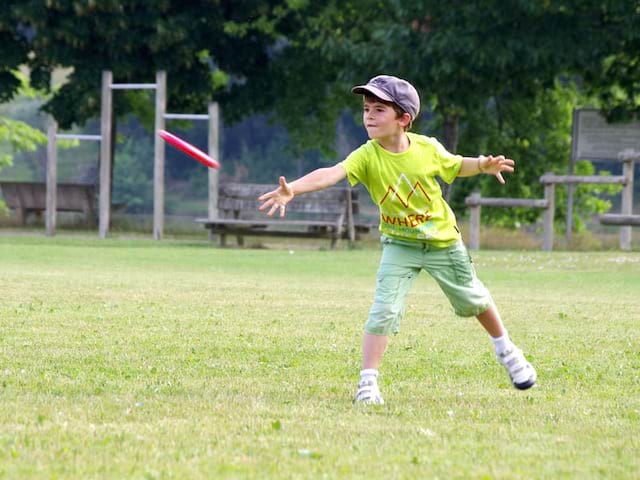 Enfant s'entrainant au freesbie pendant un grand jeu de colo 