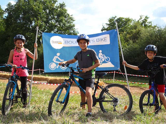 trois enfants au départ d'une course à vélo en colonie de vacances d'été