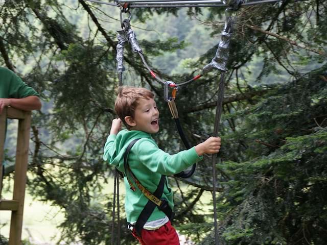 enfant faisant de l'accrobranche en colonie de vacances cet été