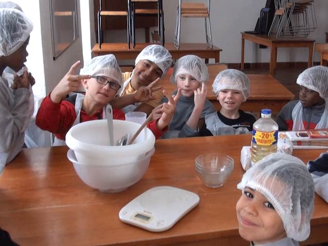 Groupe d'enfants apprenant à faire la cuisine en colonie de vacances été