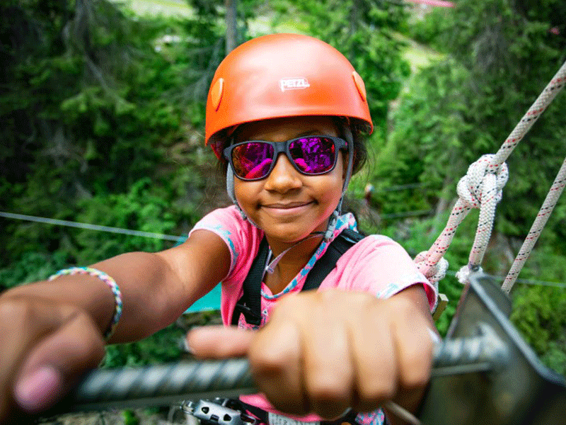 Portrait d'une enfant faisant de l'accrobranche à la montagne en colo