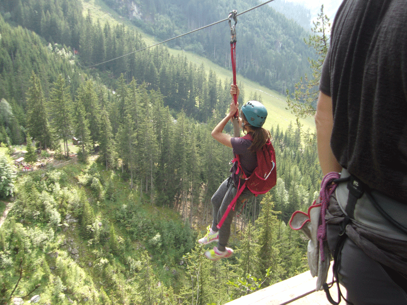Adolescents faisant de la tyrolienne en colonie de vacances à la montagne cet été