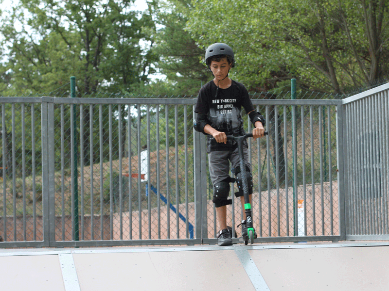 enfant faisant de la trottinette en colonie de vacances à la montagne cet été