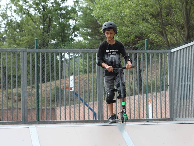 enfant faisant de la trottinette en colonie de vacances à la montagne cet été