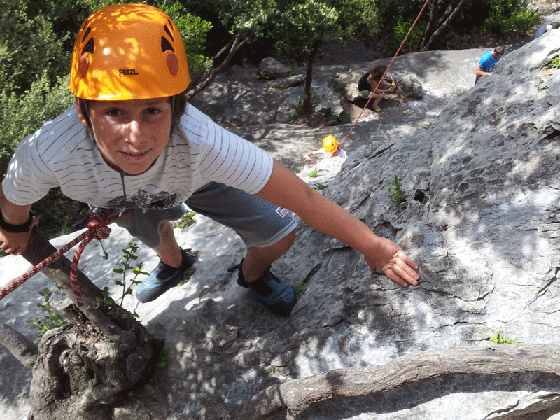 Enfant faisant de la via ferrata en colonie de vacances cet été à la montagne