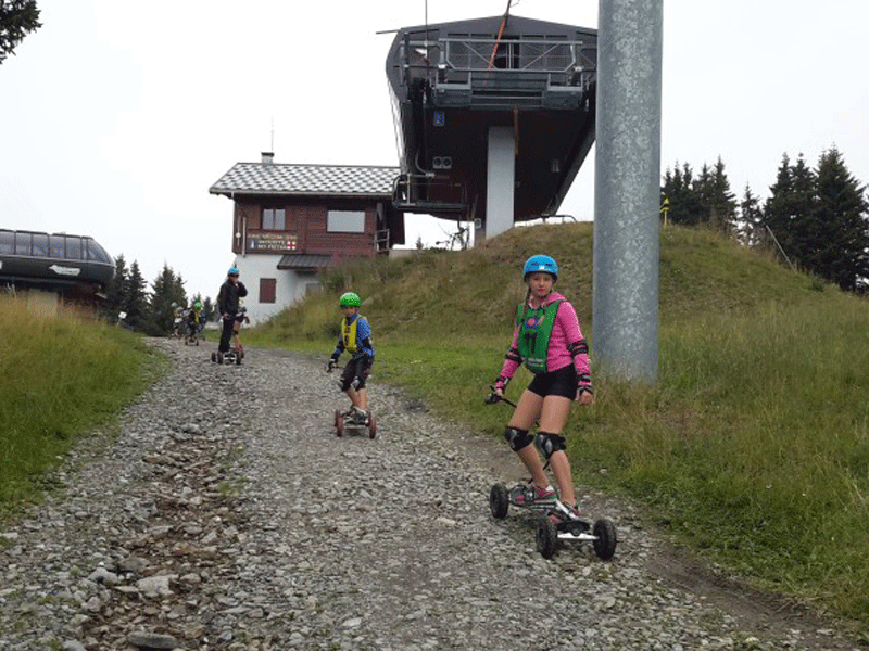 adolescents faisant du mountain board en colonie de vacances à la montagne