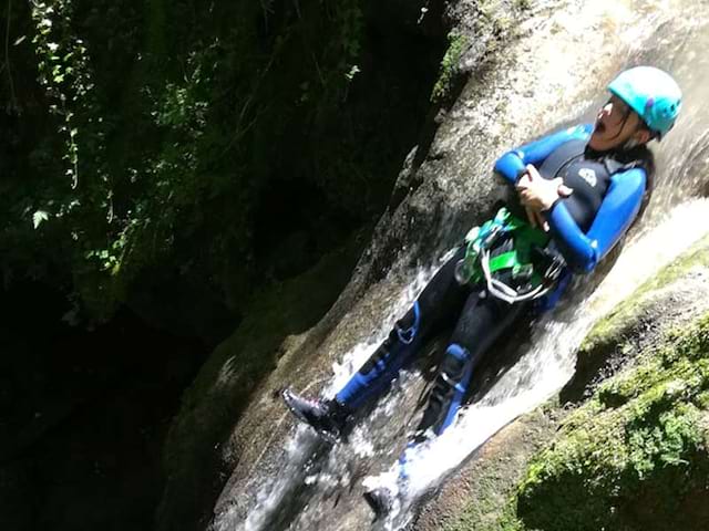 Un jeune de la colo prend un tobogan naturelle durant l'activité via ferrata de la colonie de vacances