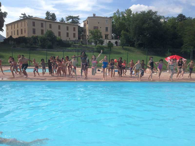 Les enfants de la colonie de vacances sautent tous ensemble dans la piscine