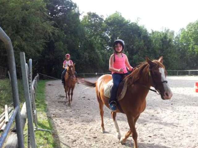 Enfants en colonie de vacances faisant de l'équitation