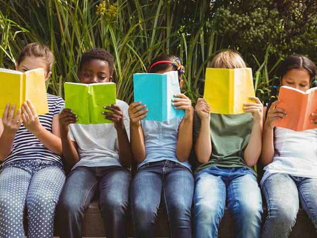 Des enfants en colonie de vacances en train de lire un livre