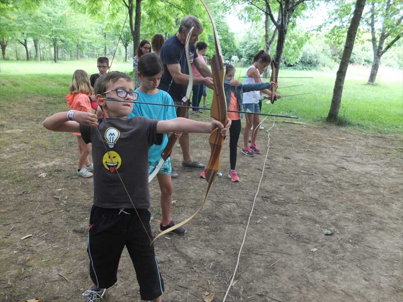 Enfants apprenant à faire du tir à l'arc en colonie de vacances d'été