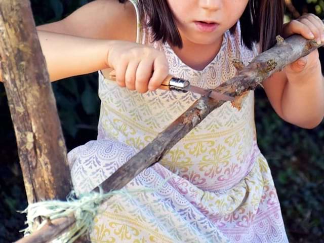 Petite fille qui taille un bâton en colonie de vacances