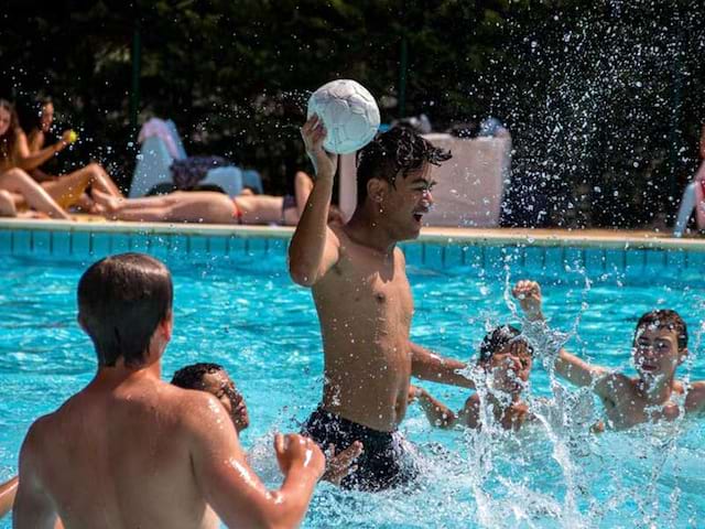 groupe d'ados jouant au ballon dans la piscine en colo cet été