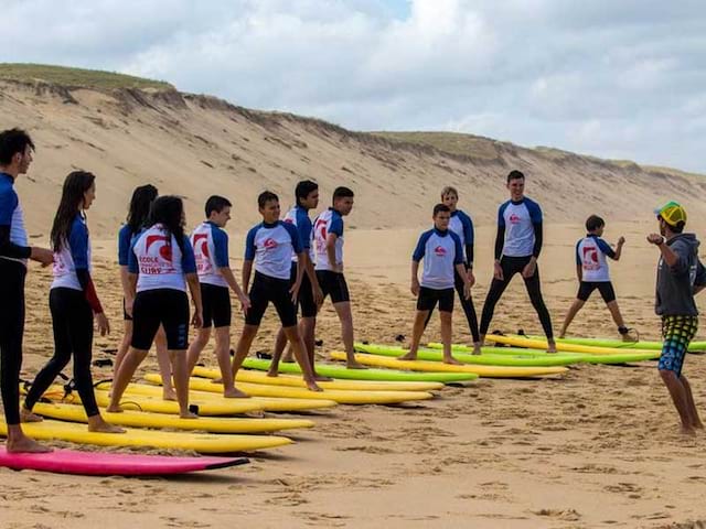 groupe d'ados avec leur planche de surf faisant des exercices cet été