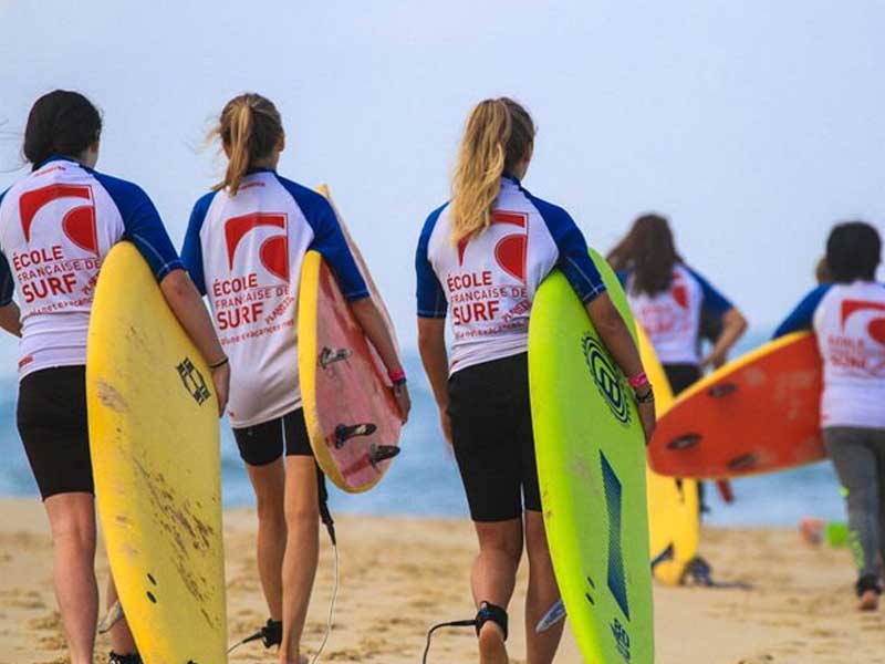 groupe d'ados avec leur planche de surf cet été en colo