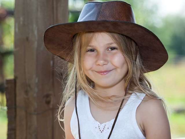 Petite fille qui souri avec un chapeau de cow-boy l'été