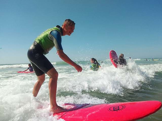 Un groupe d'adolescent fait du surf en colonie de vacances en été