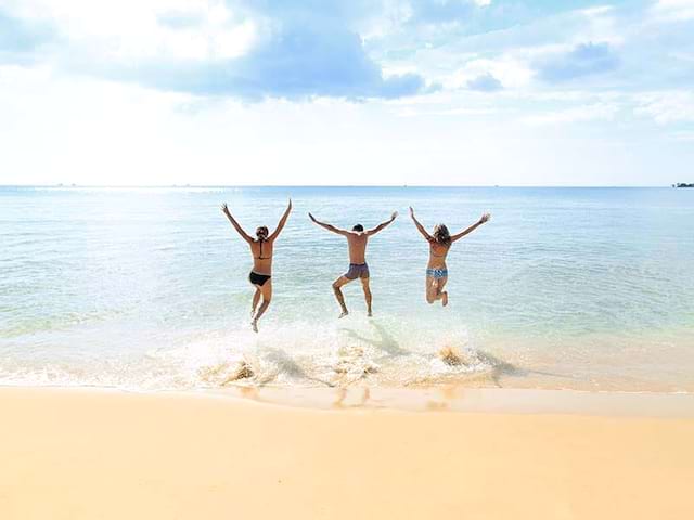 Trois jeunes en colonie de vacances, en été, sautent sur le sable pour éviter les vagues