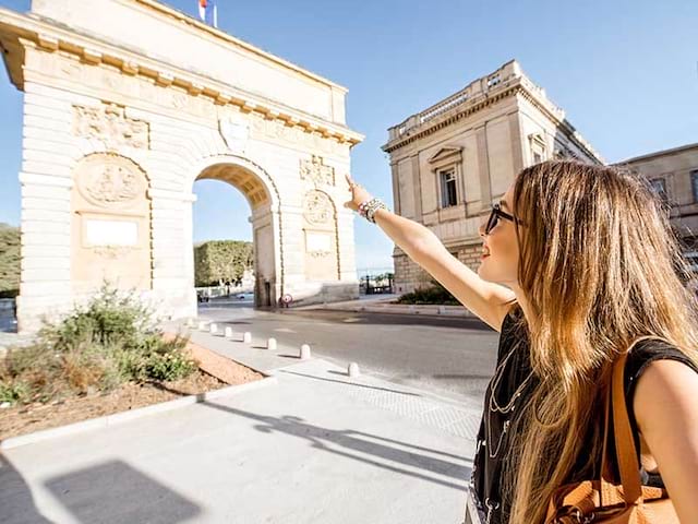 Une jeune fille pointe du doigt la porte du Peyrou de Montpellier