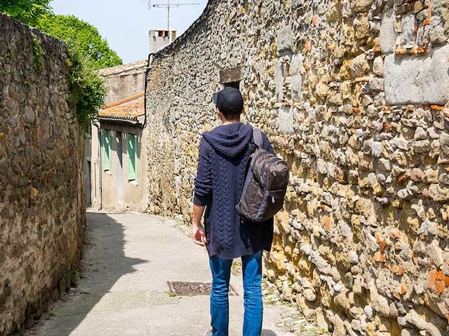 Un adolescent en colonie de vacances se balade dans les petites rues des villages d'Occitanie en été