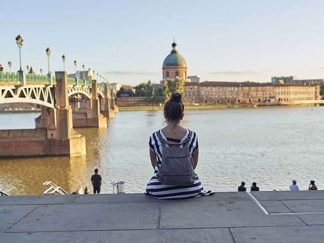 Une jeune fille se repose sur les marches des bords de la Garonne à Toulouse, en été