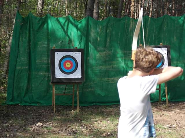 Enfant faisant du tir à l'arc en colonie de vacances d'été