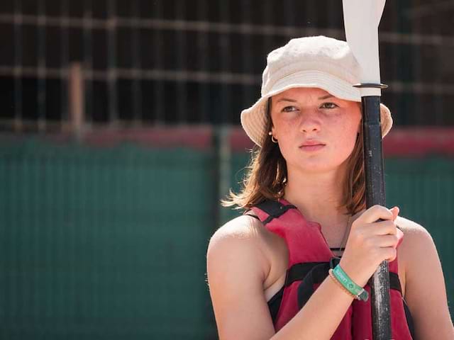 portrait d'une jeune fille avec sa pagaie en colonie de vacances surf à l'océan