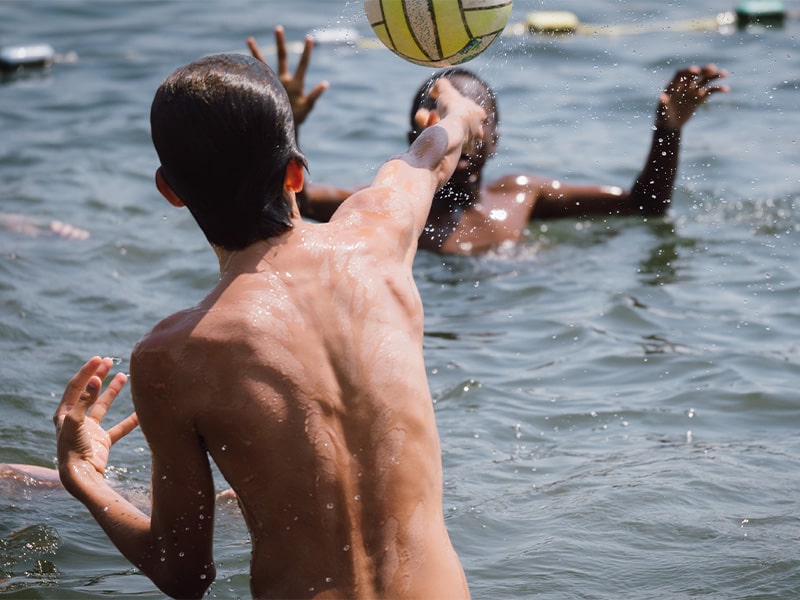 Jeunes enfants qui s'amusent dans l'eau avec un ballon lors d'une colo de vacances En Terres Bretonnes