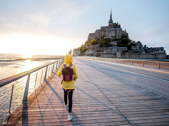 Une adolescente se promène devant le Mont-Saint-Michel en été