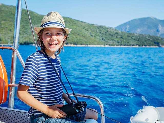 Enfant en balade à bateau en colonie de vacances à la mer