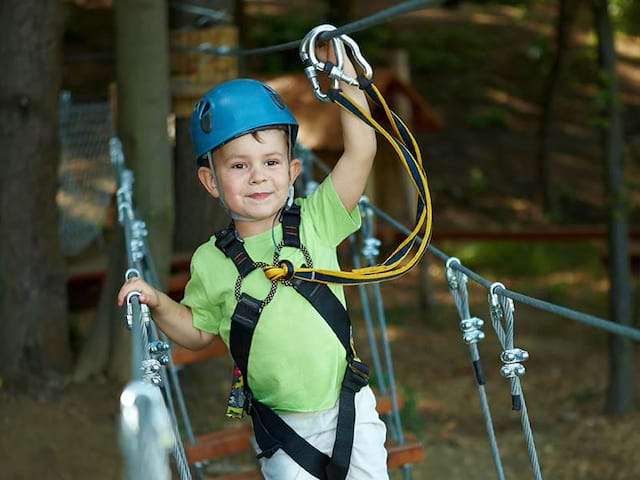 enfant faisant de l'accrobranche cet été