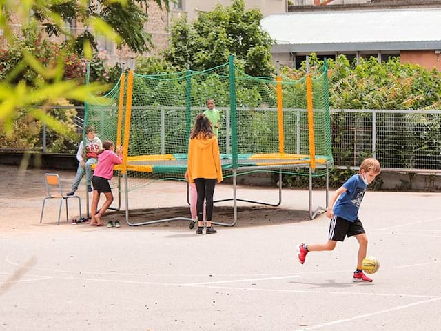 Vue sur des enfants qui s'amusent dans la cour de récréation durant les temps calmes en colo