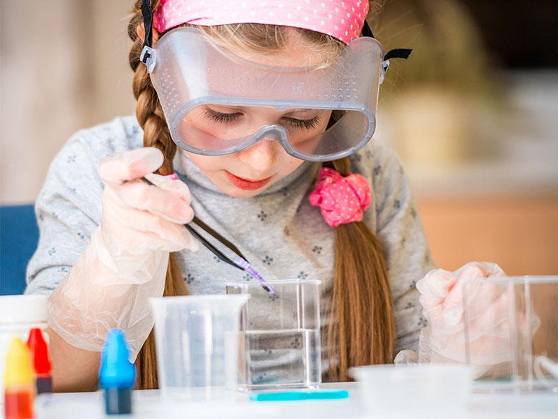 Enfant observant une expérience scientifique dans un verre en colonie de vacances d'été