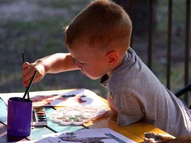 Vue sur un jeune garçon qui peint lors d'une colonie de vacances Beaux Arts et Scrapbooking