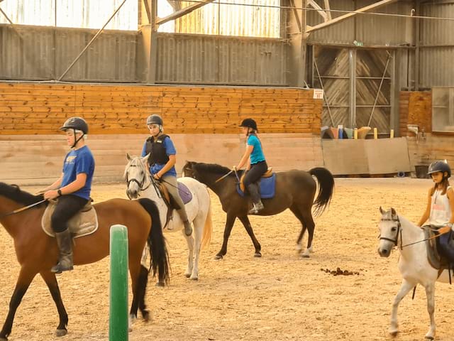 Groupe d'ados dans le manège qui font de l'Equitation en colonie de vacances 