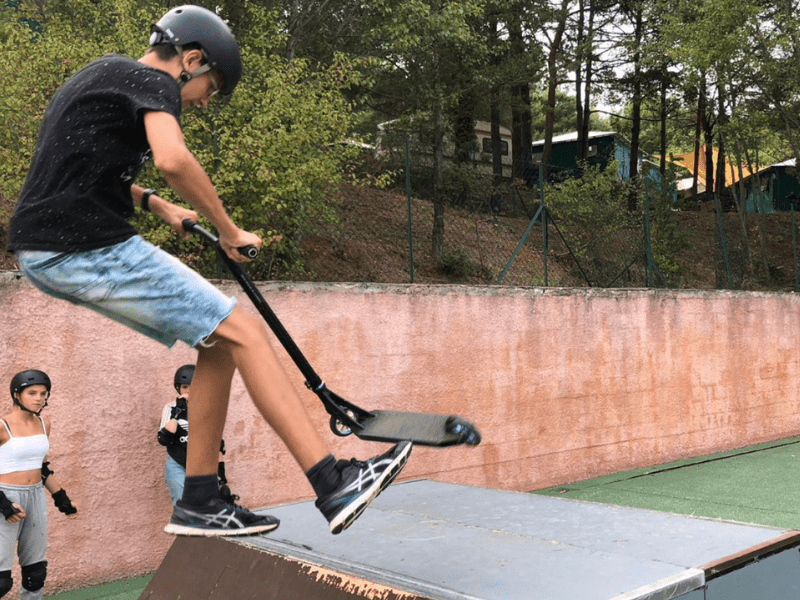 Jeune garçon en colo de vacances qui apprend le skate