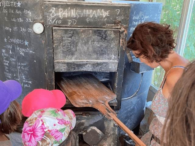 Enfants et leur encadrante qui apprennent à faire du pain en colo de vacances cuisine cet été