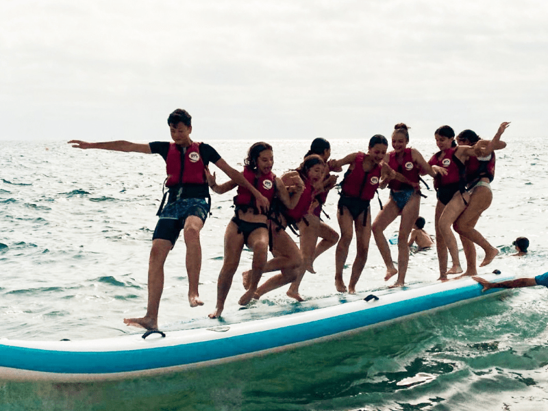Groupe de jeunes en colo de vacances qui pratiquent le stand up paddle en colo cet été