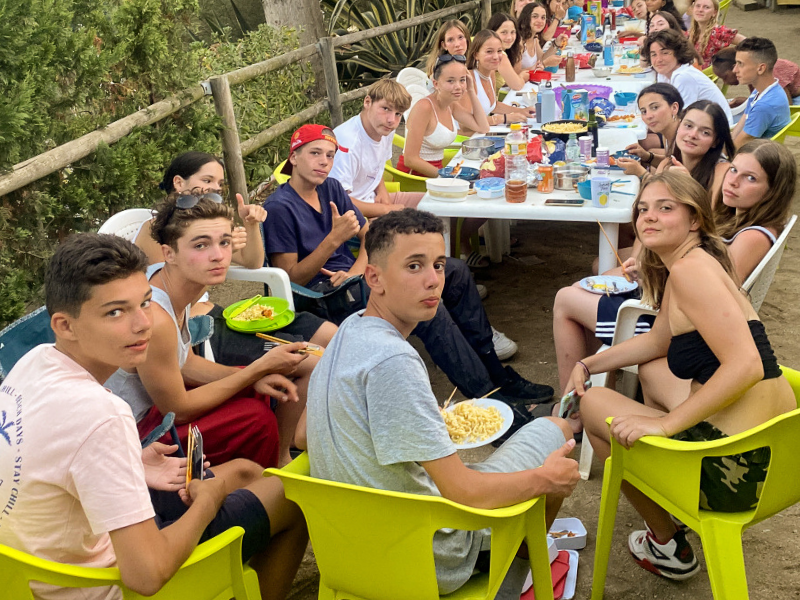 Groupe de jeunes en colo de vacances ce printemps qui prennent une pause autour d'un bon repas collectif