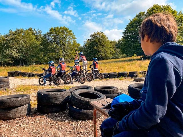 jeune garçon regardant ses copains de colo faisant de la moto