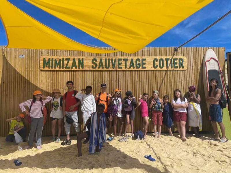 Enfants qui prennent la pose devant le poste de sauvetage à Mimizan lors de leur colo Surf